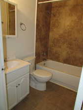 Full bathroom with toilet, tiled shower / bath combo, and vanity