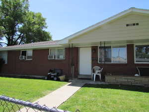 View of front of house featuring cooling unit and a front yard