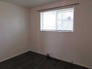 Empty room featuring a healthy amount of sunlight and dark hardwood / wood-style flooring