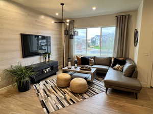 Living room featuring hardwood / wood-style flooring, wood walls, and an inviting chandelier