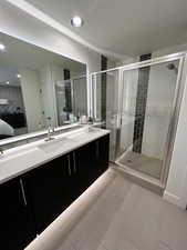 Bathroom with a shower with shower door, vanity, and tile patterned flooring