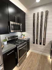 Kitchen with light hardwood / wood-style floors, backsplash, and stainless steel appliances