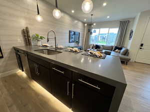 Kitchen featuring light wood-type flooring, a kitchen island with sink, pendant lighting, and sink