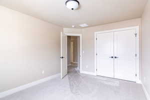 Unfurnished bedroom featuring light carpet and a closet