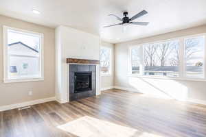 Unfurnished living room featuring ceiling fan, wood-type flooring, plenty of natural light, and a tile fireplace