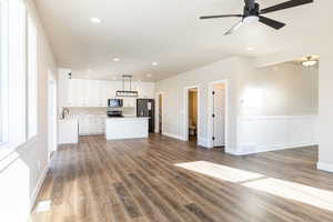 Kitchen featuring white cabinetry, stainless steel appliances, hanging light fixtures, a kitchen island, and sink