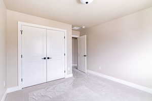 Unfurnished bedroom featuring light carpet and a closet