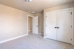 Unfurnished bedroom featuring a closet and light colored carpet