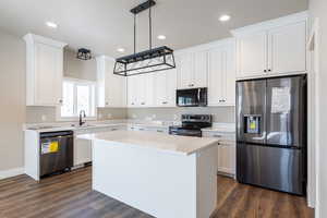 Kitchen featuring white cabinets, pendant lighting, appliances with stainless steel finishes, and a kitchen island