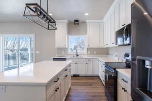 Kitchen featuring white cabinets, a kitchen island, decorative light fixtures, electric stove, and fridge with ice dispenser