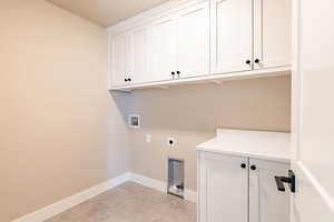 Laundry room with hookup for an electric dryer, hookup for a washing machine, and cabinets