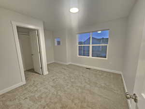 Unfurnished bedroom featuring light carpet and a closet