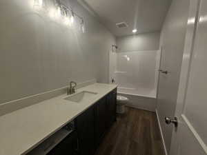 Full bathroom with toilet, vanity, hardwood / wood-style flooring, shower / bathtub combination, and a textured ceiling