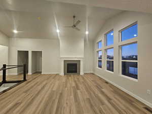 Unfurnished living room featuring vaulted ceiling, ceiling fan, and light hardwood / wood-style floors