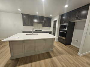 Kitchen featuring stainless steel appliances, tasteful backsplash, sink, a kitchen island with sink, and dark brown cabinets