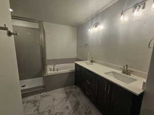 Bathroom featuring a textured ceiling, separate shower and tub, and vanity