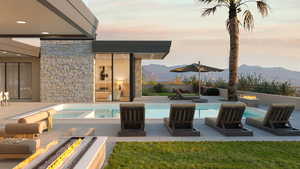 Pool at dusk featuring an outdoor fire pit, a mountain view, and a patio