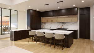 Kitchen with light wood-type flooring, a kitchen island with sink, a kitchen bar, and sink