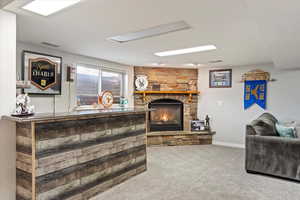 Carpeted living room with a stone fireplace