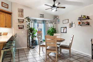 Tiled dining space featuring a textured ceiling, ceiling fan, and lofted ceiling