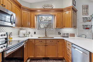 Kitchen with backsplash, appliances with stainless steel finishes, sink, and vaulted ceiling