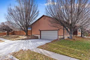 View of side of property with a garage and a lawn