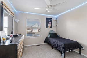 Carpeted bedroom featuring ceiling fan and multiple windows