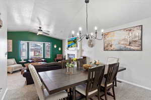 Carpeted dining space featuring ceiling fan with notable chandelier, a textured ceiling, and lofted ceiling