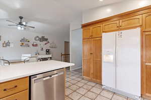 Kitchen featuring ceiling fan, stainless steel dishwasher, white refrigerator with ice dispenser, and light tile patterned floors