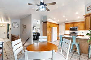 Kitchen with lofted ceiling, decorative backsplash, light tile patterned flooring, stainless steel appliances, and ceiling fan with notable chandelier