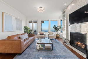 Living room featuring dark wood-type flooring, a fireplace, and crown molding