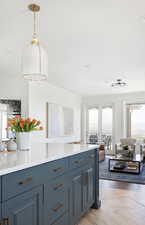 Kitchen with ornamental molding, pendant lighting, and blue cabinetry