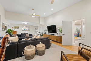 Living room with high vaulted ceiling, ceiling fan, and light wood-type flooring