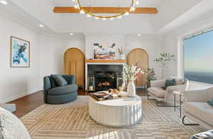 Living room with hardwood / wood-style flooring, ornamental molding, and a raised ceiling