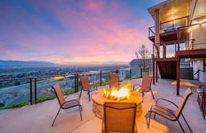 Patio terrace at dusk with a mountain view, an outdoor fire pit, cooling unit, and a balcony