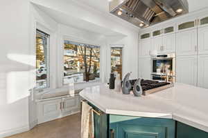 Kitchen with appliances with stainless steel finishes, a healthy amount of sunlight, wine cooler, custom range hood, and white cabinets