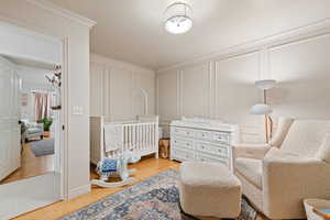 Bedroom with a crib and hardwood / wood-style flooring