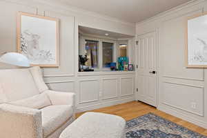 Sitting room with wood-type flooring and ornamental molding