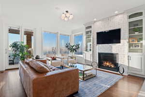 Living room featuring dark wood-type flooring, a fireplace, and crown molding