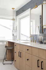 Kitchen featuring light brown cabinetry, sink, and hanging light fixtures