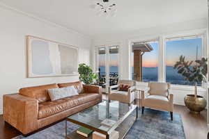 Living room with plenty of natural light, dark hardwood / wood-style flooring, ornamental molding, and a water view