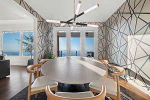 Dining room featuring dark wood-type flooring, an inviting chandelier, a water view, and french doors