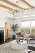 Living room featuring dark hardwood / wood-style flooring, beamed ceiling, and an inviting chandelier