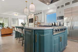 Kitchen with white cabinetry, a center island with sink, stainless steel appliances, backsplash, and hanging light fixtures