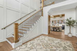 Staircase featuring coffered ceiling, a towering ceiling, hardwood / wood-style floors, and beamed ceiling