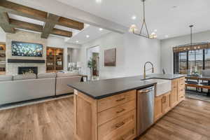 Kitchen with beamed ceiling, a fireplace, pendant lighting, stainless steel dishwasher, and sink