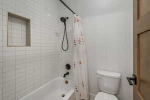 Bathroom One Upstairs featuring toilet and shower / bath combo with shower curtain