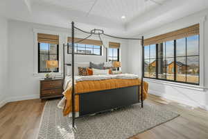 Bedroom featuring a raised ceiling, light wood-type flooring, and wood ceiling