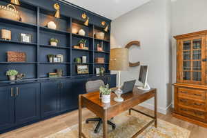 Office area featuring built in shelves and light hardwood / wood-style flooring