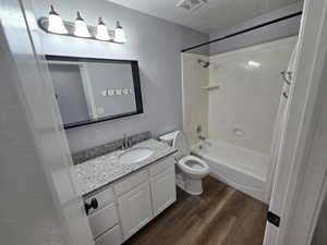 Full bathroom with a textured ceiling, shower / bathtub combination, vanity, toilet, and hardwood / wood-style flooring